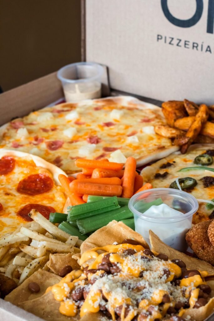 Home A delicious assortment of pizza slices, nachos, and snacks in a pizzeria box. Perfect for a party.